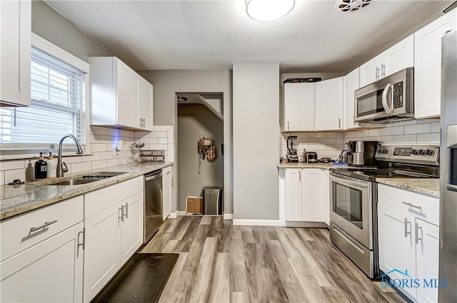 kitchen with white cabinets, light stone countertops, sink, and appliances with stainless steel finishes