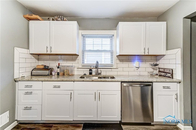 kitchen with dishwasher, white cabinets, sink, tasteful backsplash, and light stone counters