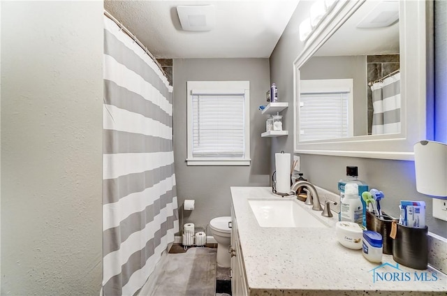 bathroom with vanity, toilet, and a healthy amount of sunlight