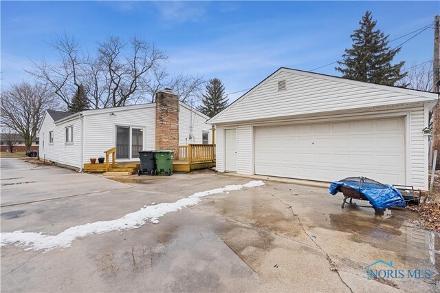 view of property exterior featuring an outbuilding, a garage, and a deck