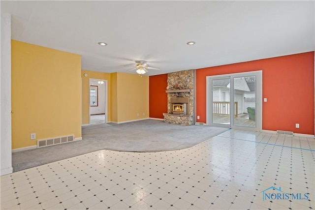 unfurnished living room with a stone fireplace, light carpet, and ceiling fan