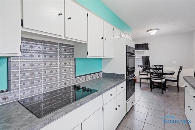 kitchen featuring light tile patterned flooring, white cabinets, and black appliances