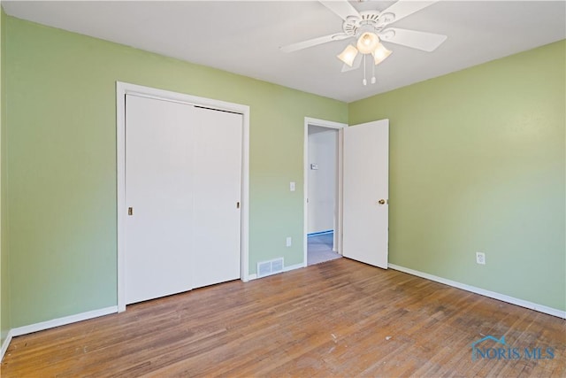 unfurnished bedroom featuring hardwood / wood-style flooring, ceiling fan, and a closet