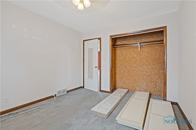 unfurnished bedroom with ceiling fan, light carpet, and a closet