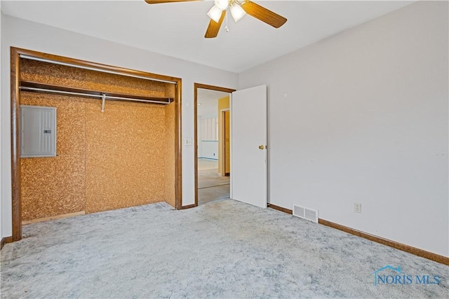 unfurnished bedroom featuring light carpet, electric panel, a closet, and ceiling fan