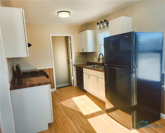 kitchen with black appliances, light wood-type flooring, backsplash, white cabinets, and sink