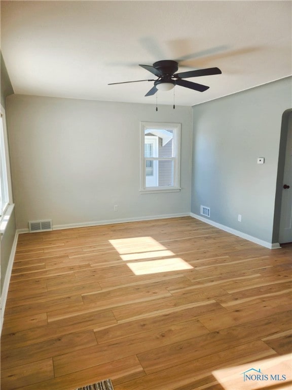 spare room featuring ceiling fan, light wood-type flooring, and a wealth of natural light