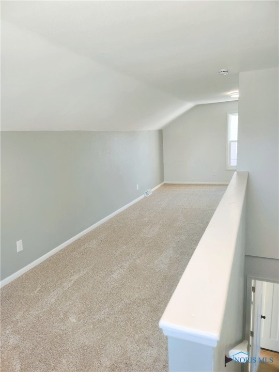 additional living space featuring vaulted ceiling and light carpet