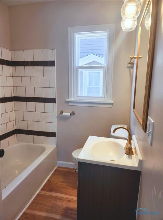 full bathroom featuring toilet, vanity, hardwood / wood-style floors, and washtub / shower combination