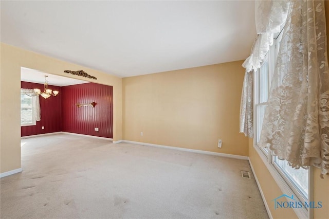 unfurnished room with an inviting chandelier and carpet floors