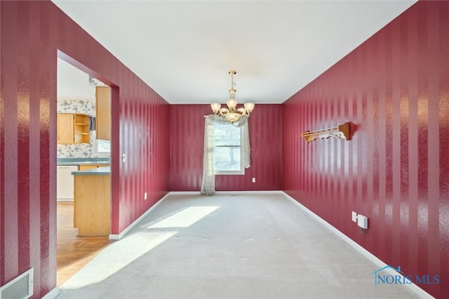 unfurnished dining area with a notable chandelier and light carpet