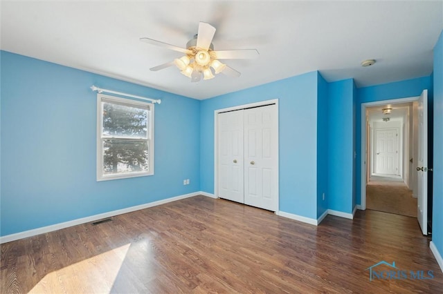 unfurnished bedroom featuring dark hardwood / wood-style flooring, a closet, and ceiling fan