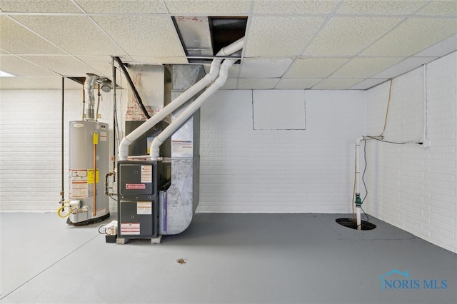 basement with brick wall, water heater, and a paneled ceiling