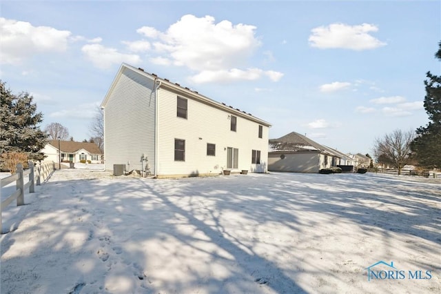 snow covered back of property featuring central AC