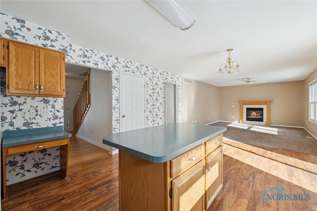 kitchen featuring a kitchen island, dark wood-type flooring, decorative light fixtures, and ceiling fan with notable chandelier