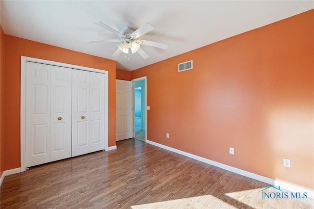 unfurnished bedroom with wood-type flooring, a closet, and ceiling fan