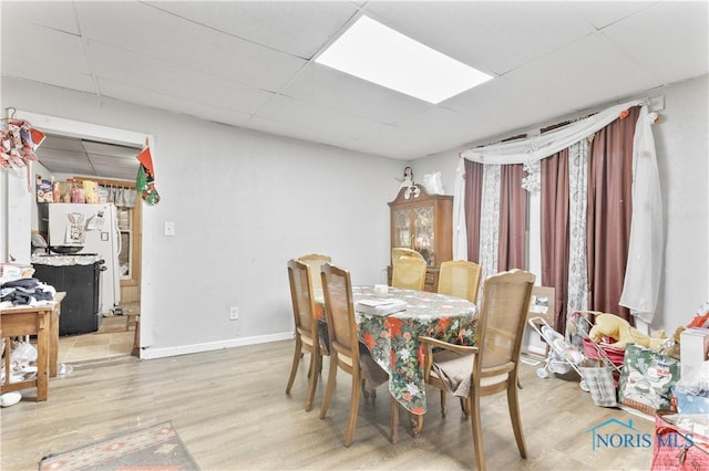 dining area featuring a drop ceiling and wood-type flooring