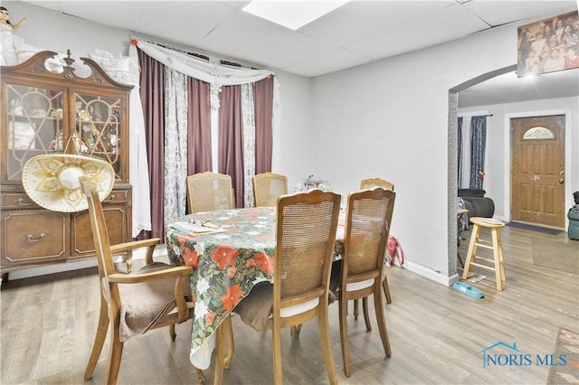 dining space featuring a drop ceiling and hardwood / wood-style flooring