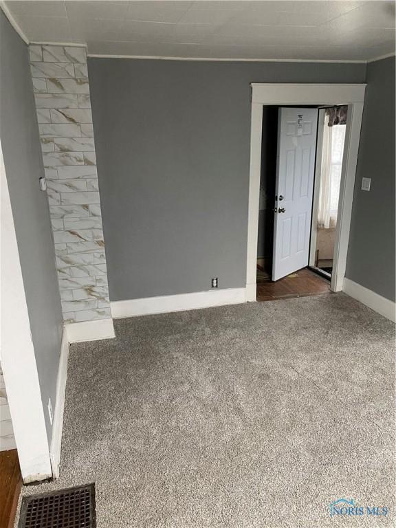 carpeted spare room featuring visible vents, baseboards, and ornamental molding