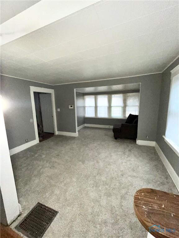 unfurnished living room featuring plenty of natural light and carpet flooring