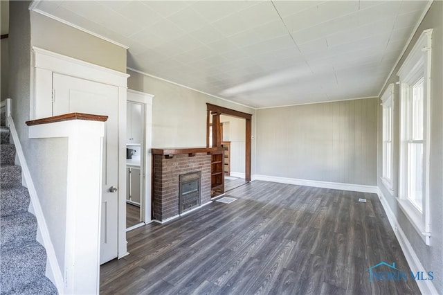 unfurnished living room featuring dark hardwood / wood-style floors, crown molding, and a brick fireplace