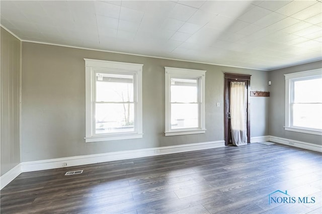 empty room with dark hardwood / wood-style flooring and ornamental molding