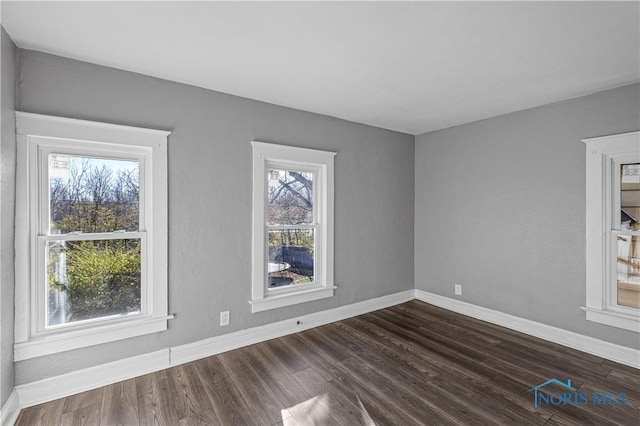 spare room featuring dark hardwood / wood-style flooring and a wealth of natural light