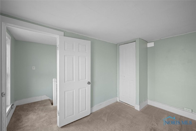 unfurnished bedroom featuring light colored carpet and a closet