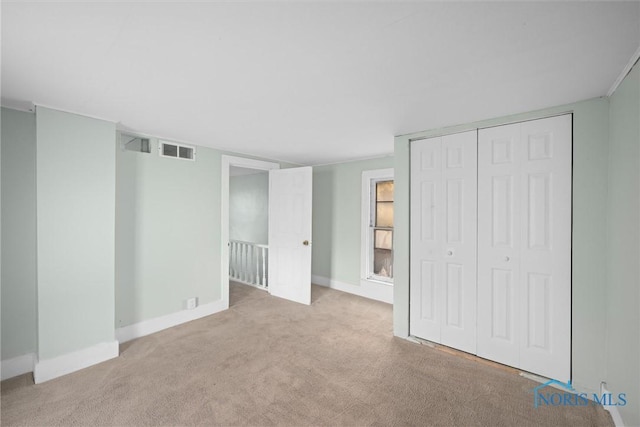 unfurnished bedroom with light carpet and a closet