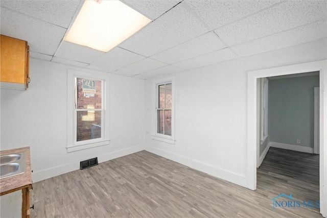 unfurnished room with hardwood / wood-style flooring, a paneled ceiling, and sink