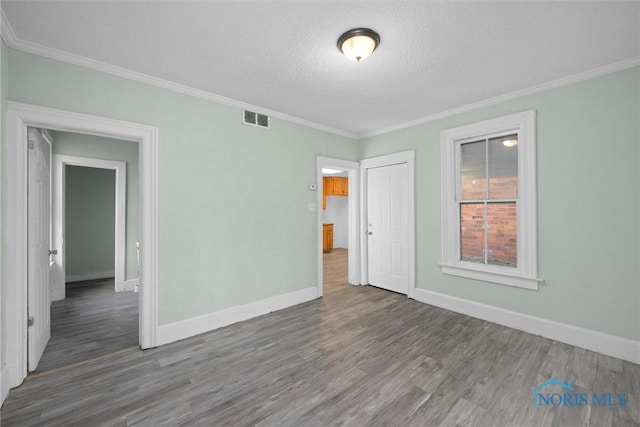 unfurnished room with dark hardwood / wood-style flooring, a textured ceiling, and ornamental molding