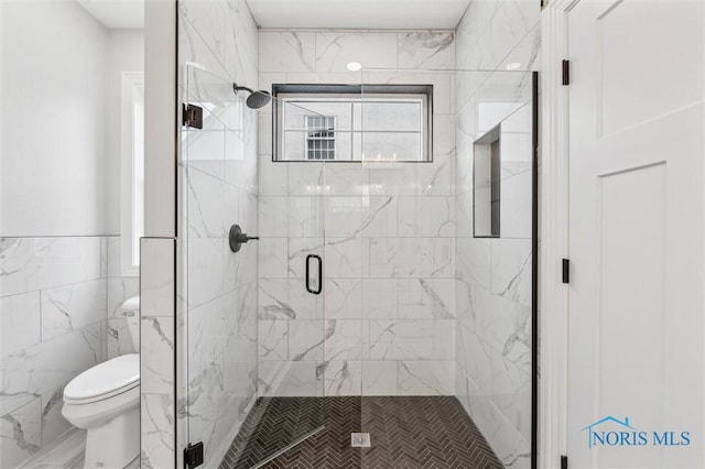 bathroom featuring a shower with door, tile walls, and toilet