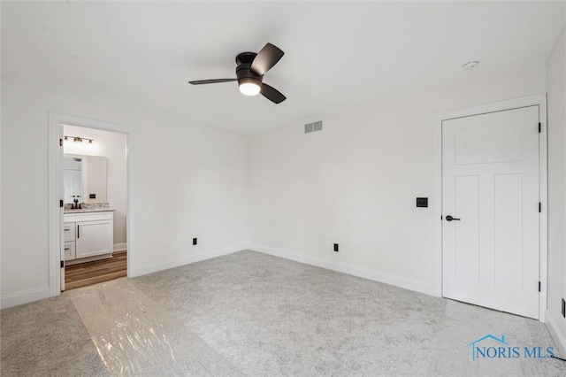 unfurnished bedroom featuring ensuite bath, ceiling fan, sink, and light colored carpet