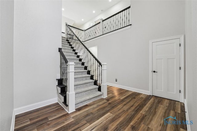 stairway featuring wood-type flooring and a high ceiling