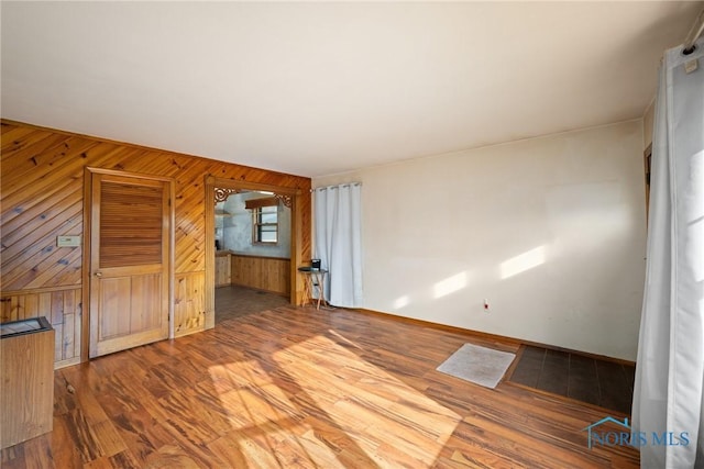 unfurnished living room featuring dark hardwood / wood-style flooring and wood walls