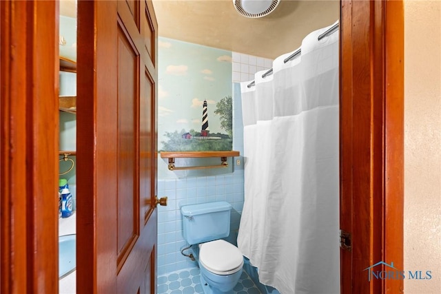 bathroom featuring toilet and tile walls