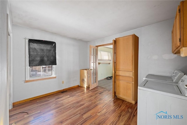 laundry area with cabinets, hardwood / wood-style floors, and washing machine and clothes dryer