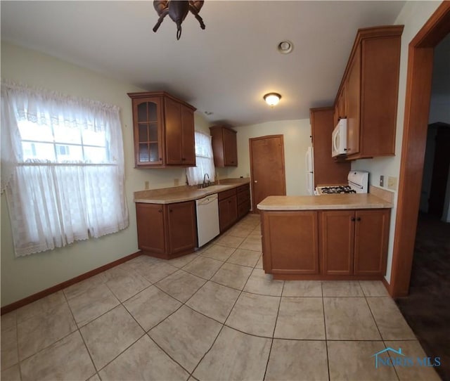 kitchen featuring sink, white appliances, light tile patterned floors, and kitchen peninsula