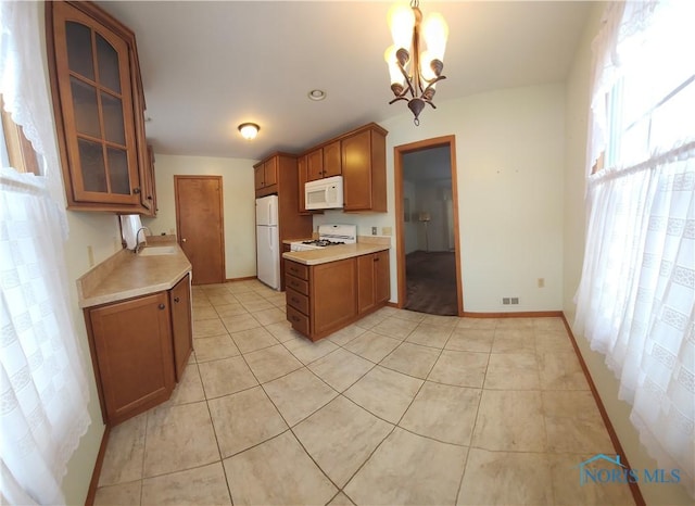 kitchen featuring an inviting chandelier, light tile patterned floors, white appliances, hanging light fixtures, and sink