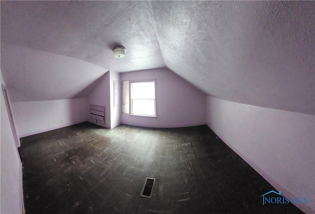 bonus room featuring vaulted ceiling and a textured ceiling