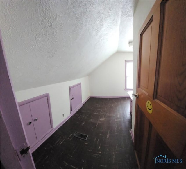 bonus room featuring vaulted ceiling and a textured ceiling