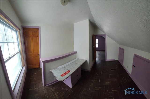 corridor with a textured ceiling and lofted ceiling