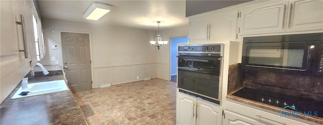 kitchen with sink, black appliances, decorative light fixtures, a notable chandelier, and white cabinets