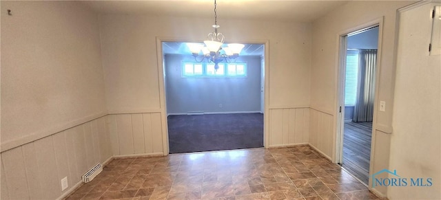 unfurnished dining area featuring a chandelier