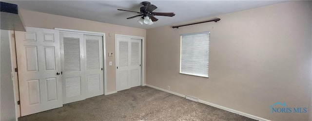 unfurnished bedroom featuring carpet floors, ceiling fan, and multiple closets