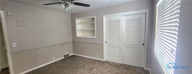 unfurnished bedroom with ceiling fan, a closet, and dark carpet