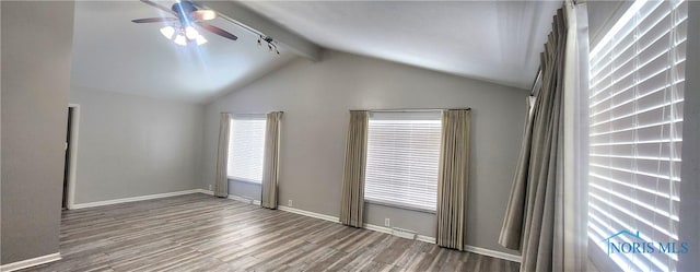 spare room featuring hardwood / wood-style flooring, lofted ceiling with beams, ceiling fan, and plenty of natural light