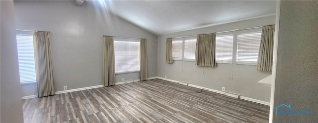 spare room featuring a healthy amount of sunlight, dark hardwood / wood-style flooring, and vaulted ceiling