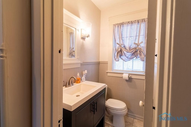 bathroom with tile patterned flooring, vanity, tile walls, and toilet