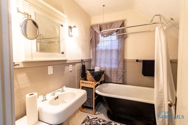 bathroom with a tub to relax in, tile patterned floors, and sink